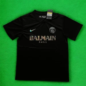 Svart PSG x Balmain fotbollströja Nike - Svart fotbollströja från Nike i samarbete med PSG och Balmain. Tröjan har korta ärmar, rund hals och är gjord i ett lätt, andningsbart material. Framsidan pryds av holografiska loggor för Balmain och PSG samt Nike Swoosh. Perfekt för dig som vill sticka ut på planen.