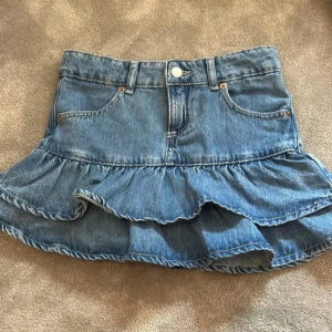 Blå jeanskjol med volang - Supersöt blå jeanskjol med volang nertill!❤️ kommer ifrån Zara, använd ett fåtal ggr och ligger bara i garderoben och får inte så mycket användning🫶🏼🫶🏼 storlek 152 men passar xxs/xs💕
