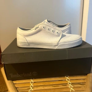 Vita Vans sneakers i canvas - Klassiska vita Vans sneakers i canvas med låg profil och rund tå. Skorna har platt sula och kommer med vita skosnören. Perfekta för en clean och stilren look till vardags.