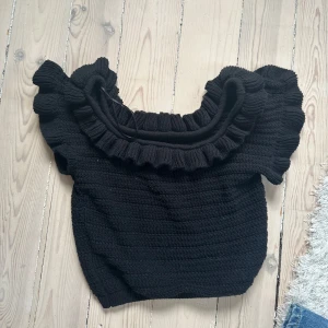 Svart stickad topp med volang - Oanvänd topp, den fick ett konstigt ljus på bilden. Men den är i nyskick.