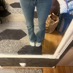 Bootcut jeans i ljusblå denim från Nelly - Bootcut jeans i ljusblå denim från Nelly med låg midja, dubbla knappar och framfickor med markerade sömmar. Jeansen har en klassisk bootcut-passform som sitter snyggt på höften och släpper ut vid benslutet. Perfekta för en avslappnad och trendig look. Nypris 699 kr.