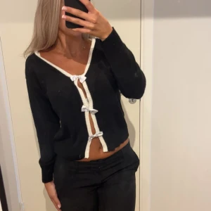 Cardigan med rosetter - Supersöt svart kofta med vita rosetter!