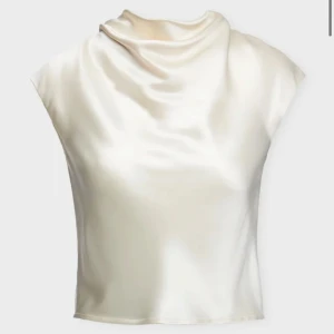Champagnefärgad satintopp med draperad hals - Säljer en elegant, ärmlös topp i champagnefärgad satin med snygg draperad halsringning. Toppen har en slät, glansig yta och rak passform som ger en lyxig känsla. Perfekt för dig som gillar stilrena och trendiga plagg.