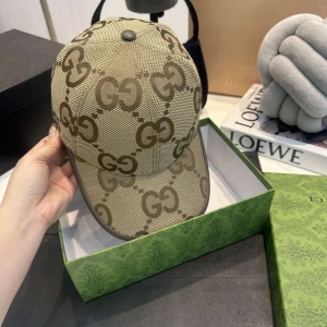 Beige keps från Gucci med GG-mönster - Snygg beige keps från Gucci med det klassiska GG-logomönstret i brunt över hela kepsen. Kepsen har böjd skärm, justerbar rem bak och är tillverkad i ett slitstarkt canvasmaterial. Perfekt accessoar för att lyfta din outfit med lyxig känsla.