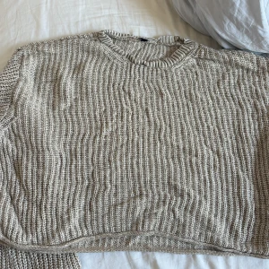 Beige stickad tröja med struktur - Säljer en beige stickad tröja med grov struktur och rund hals. Tröjan har en avslappnad passform och ribbade detaljer vid hals och nederkant. Perfekt för lager-på-lager och chill dagar.