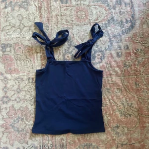 Säljer en jättefin unik mörkblå linnetopp Holly & Whyte - Supersöt mörkblå topp från Holly & Whyte i storlek xs med axelband som kan knytas till stora rosetter vilket är väldigt gulligt.Den är perfekt till sommaren&hösten och den är knappt använd så i väldigt bra skick🌸Den är i bra material, är lite kortare i modellen, unik, har fin passform och är enkel att styla👍🏻Skriv om funderingar, lämna gärna omdöme om köpt och priset kan diskuteras😊
