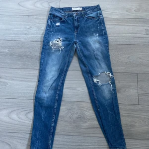 Blå ripped skinny jeans  - Snygga blå skinny jeans från Gina tricot i storlek 34. Jeansen har slitna detaljer och stora hål vid knäna. 