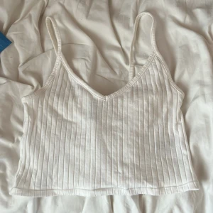 Vit ribbad linnetopp med smala axelband - Superfräsch vit croppad linnetopp med smala axelband och v-ringad hals. Knappt använd då jag tycker att den är lite för kort på mig!💕