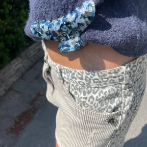 Jeansshorts med leopardmönster - Unika shorts med cool mix av smala beige/vita ränder och leopardmönster i svart och grått. Låg midja, klassisk jeansmodell med knapp och dragkedja. Snygga detaljer som små slitningar och vikta benslut. Perfekta för dig som vill sticka ut i sommar! Omsydd för en mer trending och unik look. Billigt, snyggt och miljövänligt! Storlek S/M