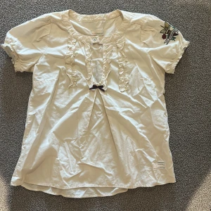 Vit blus från Odd Molly - Supersöt vit blus från Odd Molly med korta puffärmar, volangdetaljer framtill och en liten rosett. Pris går att diskutera!🤍Passar xs-s