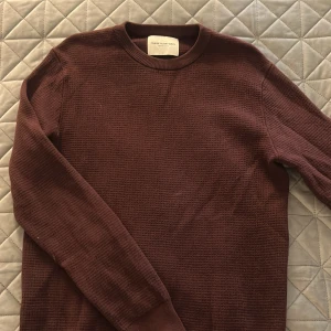 Vinröd stickad tröja These Glory Days - Säljer en vinröd stickad tröja från These Glory Days. Tröjan har rund halsringning, lång ärm och en diskret textur i materialet. Perfekt för dig som gillar stilrena och enkla plagg med en twist. Passar dig som vill ha en basic men snygg look.