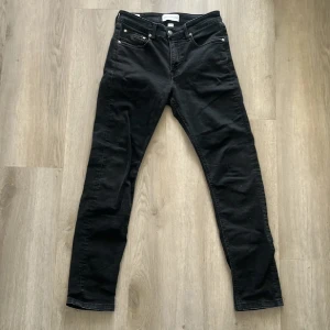 Svarta Calvin Klein slim taper jeans - Svarta jeans från Calvin Klein med slim taper passform och Infinite Flex-material. Klassisk femficksmodell med dragkedjegylf och diskret CK-detalj på fickan. Snygga och stilrena jeans som sitter tajt men ändå flexibelt.