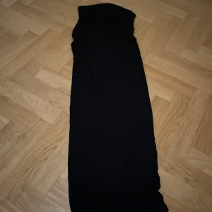 Svart kjol från Gina Tricot - Elegant svart lång kjol från Gina Tricot. Perfekt för en stilren look med en smickrande passform. Kjolen har en klassisk design som passar till många tillfällen. Snyggt rynkad 