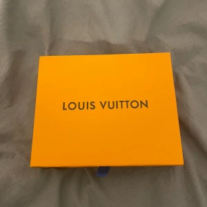 Svart plånbok med mönster - Snygg svart plånbok med det klassiska monogrammönstret. Plånboken har flera fack för kort och en transparent ficka för ID. Perfekt för att hålla ordning på dina värdesaker med stil.