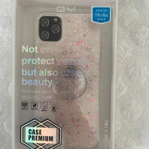 Glittrigt mobilskal för iPhone 11 Pro Max - Snyggt och glittrigt mobilskal från för iPhone 11 Pro Max. Skalet har en transparent design med färgglada glitterdetaljer som ger din telefon ett unikt utseende. Perfekt för att skydda och samtidigt styla din mobil. Säljer eftersom den inte passar min mobil💕