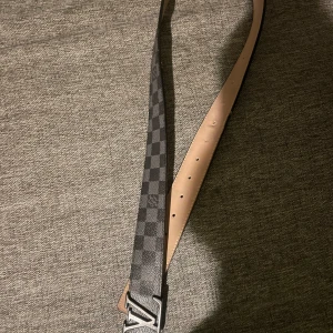 Rutig bälte  - Säljer ett stilrent bälte med ett klassiskt rutigt mönster i svart och grått. Perfekt för att ge en lyxig touch till din outfit. Skriv innan ni köper 