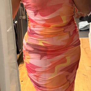 Färgglad klänning från Boohoo - Säljer en färgglad klänning från Boohoo med abstrakt mönster i rosa, orange och gult. 