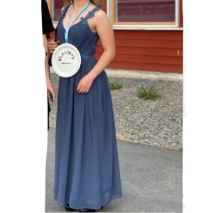 Blå långklänning med spetsdetaljer - Blå/marinblå balklänning med spetsdetaljer vid axlarna och v-ringad design. Köpt på bubbleroom i storlek S.