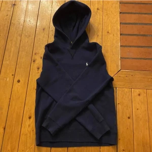 Mörkblå hoodie från Ralph Lauren - Säljer en stilren mörkblå hoodie från Ralph Lauren. Tröjan har en klassisk design med huva och långa ärmar. Perfekt för en avslappnad look. 🧢