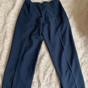 Mörkblå kostymbyxor med gulddetalj - Snygga mörkblå kostymbyxor med en elegant gulddetalj framtill. Byxorna har en elastisk midja för extra komfort och en stilren design som passar perfekt till både vardag och fest. Perfekta för en chic look! Priset går att diskutera💞