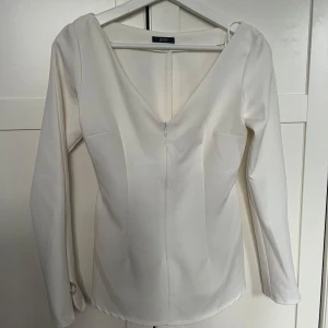 Vit långärmad topp  - Vit långärmad topp med dragkedja i fram. Tröjan är figursydd och sitter så fint på. Perfekt till dag och kväll! 💗