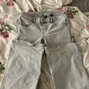 Lågmidjade jeans - Snygga grå jeansbyxor från Gina Tricot i storlek 40. De har en klassisk femficksdesign och en knappgylf. Perfekta för en stilren look.