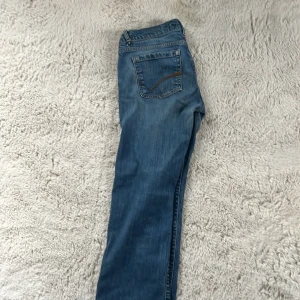 Vintage jeans med tryck  - Säljer ett par klassiska blå jeans från Lindex. De har en blandning mellan rak och bootcut passform med femficksdesign och knappgylf. Perfekta för en avslappnad stil. Jeansen har tyvärr ett hål på båda sidorna som syns på sista bilden men går super enkelt att fixa med lite nål och tråd! Original priset ligger mellan 400-700kr.