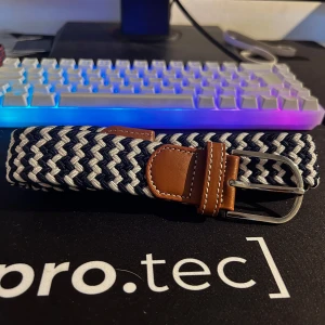 Stilrent flätat bälte  - Ett snyggt och stilrent flätat bälte i klassiskt marinblått och vitt zigzag mönster. Ljusbruna läderdetaljer och silverspänne ger en elegant finish. Bältet är elastiskt och bekvämt med flexibel passform. Har även två andra bälten på min profil går nog att lösa ett paketpris för alla.