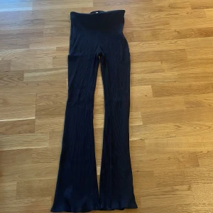 Svarta ribbade byxor - Snygga svarta ribbade byxor med hög midja och utsvängda ben. Perfekta för en trendig look. Passar bra till både vardag och fest.