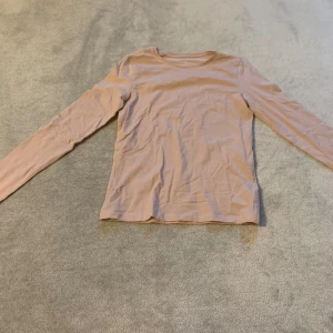 Beige långärmad tröja - Säljer en stilren beige långärmad tröja. Perfekt för lager-på-lager under kyligare dagar. Enkel design som passar till det mesta.