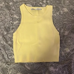 Gul ärmlös topp från Zara - Säljer en topp från Zara. Perfekt för varma dagar med sin enkla och fräscha design. Endast använd en gång!