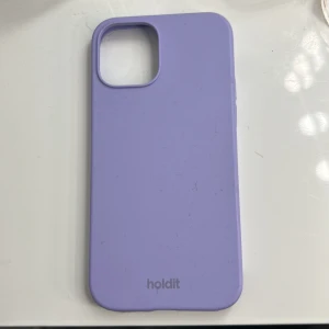 Lila mobilskal från Holdit. iPhone 12/12 PRO  - Säljer ett stilrent lila mobilskal från Holdit. Skalet är designat för att skydda din telefon och har exakta utskärningar för knappar och portar. Perfekt för att ge din mobil en färgglad touch! Den har skador och är lite sönder men ordinarie pris är 150kr.