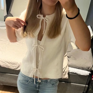 Vit stickad topp  - Säljer en söt vit kortärmad topp med knyt rosetter. Passar bra till jeans eller kjol💞 helt ny med lapp kvar 