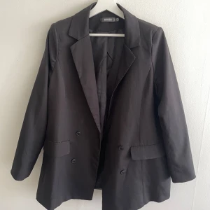 Svart kavaj Missguided - Svart oversize kavaj med axelvaddar från Missguided, storlek 36.