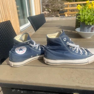 Blå Converse  - Säljer ett par klassiska blå Converse All Star sneakers i storlek 37. Skorna är använda en del men är ändå i bra skick! 