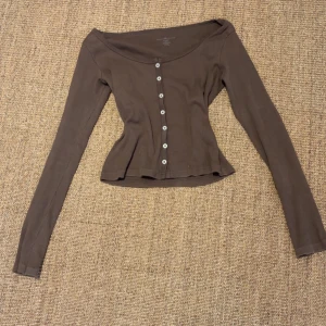 Brun ribbad kofta med knappar - Säljer en brun ribbad kofta med knappar framtill från brandy Melville. Koftan har en figurnära passform och långa ärmar. Perfekt för en stilren och bekväm look. Står ingen storlek men skulle säga XS