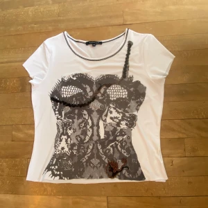 T-shirt med coolt tryck  - Tisha från kapalua med delvis glittrigt och grått tryck, ärmarna och nederkanten är klippta kortare men är i superbra skick. Passar typ alla storlekar då den är stretchig. Fett unik och cool tröja!