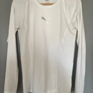 Vit långärmad tröja från Puma - Säljer en stilren vit långärmad tröja från Puma. Perfekt för träning eller som ett basplagg. Tröjan har en diskret Puma-logga på bröstet och är tillverkad i ett mjukt och bekvämt material.