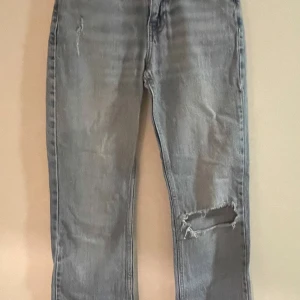 Ljusa jeans med slitningar - Snygga ljusa jeans från Gina tricot med slitningar på ena benet. Hålet på knät har töjts ut under tiden jag ägt dom. 