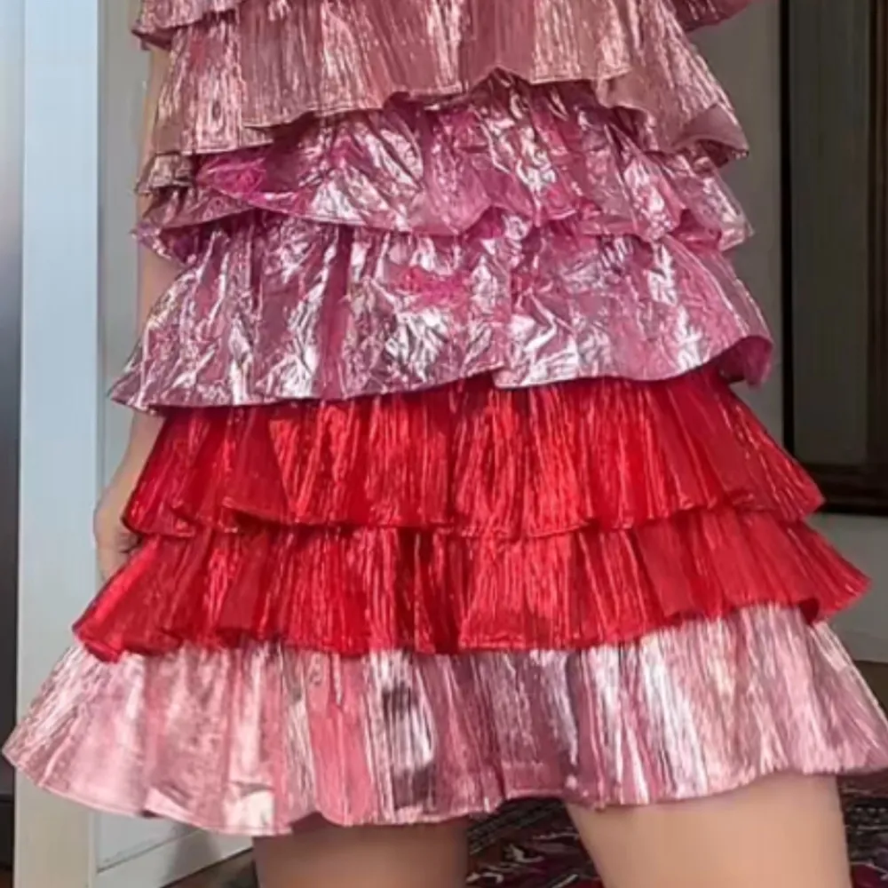 Säljer en färgglad klänning med volanger i olika nyanser av rosa och rött. Aldrig använda ! Endast testad !! Klänningen har axelband och har en kort längd, perfekt för en festlig look. Materialet ger en glansig finish som verkligen sticker ut. . Mekot.