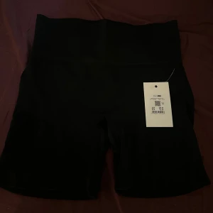 Gym shorts - Svarta cykel shorts från Bikbok. Gjord i träningsmaterial med en slimmande effekt vid midjan. Går att använda till träning eller för att ha under klänningar. Storlek L-XL men passar mer en M-L, för små för mig. Ordinarie pris 229kr