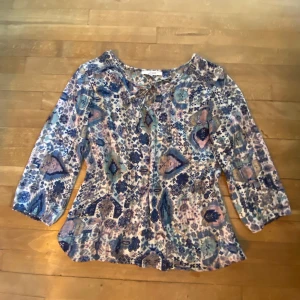 Blå mönstrad blus - Säljer min favvoblus som inte går att köpa! Den är i blå, rosa och vit, perfekt skick! 💘 Trekvartsärmad och rosett som man knyter i fram. Mönstret är verkligen så vackert
