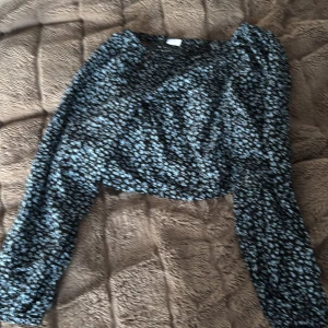 Blommig långärmad topp från Lindex - Säljer en söt blommig topp från Lindex i svart och blått. Toppen har långa ärmar och ett fint blommönster som ger en romantisk känsla. Perfekt för både vardag och speciella tillfällen. 🌸