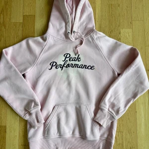 Rosa hoodie från Peak Performance - Säljer en snygg baby rosa hoodie från Peak Performance. Den har en klassisk känguruficka och justerbar huva med dragsko. 
