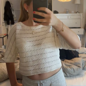 Vit stickad croppad topp från Kappahl - Säljer en söt vit stickad croppad topp från Kappahl. Tröjan har korta ärmar och ett hålmönster som ger en luftig känsla. Perfekt till sommaren och enkel att matcha med både jeans och kjol. Nypris 399 kr