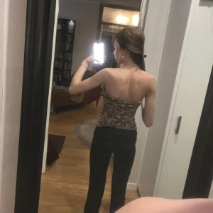 Leopardmönstrad tubtopp från H&M - Säljer en snygg leopardmönstrad tubtopp från H&M i beige och svart. Toppen är axelbandslös och har en tight passform som sitter snyggt på kroppen. Perfekt att styla med jeans eller kjol för en trendig look.