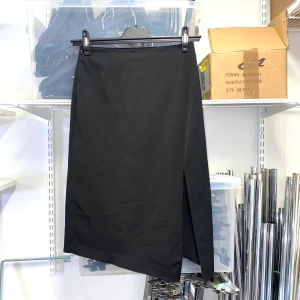 Svart asymmetrisk kjol med slits - En svart kjol med snygg asymmetrisk nederkant och slits framtill. Materialet känns mjukt och följsamt. Knäpps med dragkedja i midjan.  Strl: 38-40, stretchig i tyg, ej midja.  Mått: Midja 70 cm.   /   Spara skärmtid, besök våra butiker i Sthlm, Malmö & Gbg. New arrivals daily + studentrabatt i alla våra butiker! Hitta till din närmsta butik på humansecondhand.se.   HUMANA Second Hand erbjuder 14 dagars retur, även via plick. Returer skickas med PostNord. Vid retur kontakta support@plick.se.