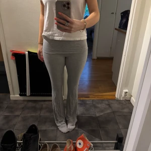 Grå mjukisbyxor med utsvängda ben - Säljer ett par ljusgrå mjukisbyxor med utsvängda ben och hög midja. Byxorna är i mjukt och stretchigt material, perfekta för en avslappnad stil. Passformen är tight upptill och vidare nertill.
