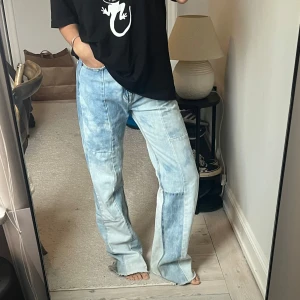 Ljusblå jeansbyxor från Pull&Bear - Säljer ett par ljusblå jeansbyxor från Pull&Bear med patchwork-detaljer och raka ben. Byxorna har hög midja, klassiska fickor och en unik tvättad look som ger en cool vibe.