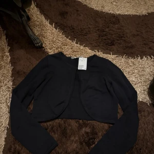 Svart bolero  - Säljer en svart croppad bolerotopp från h&m som är helt ny med prislapp, köpt online för 249kr hos barnavdelningen i storlek 170 14Y+ men passar dock folk med storlek S-M samt säljer den för 149kr!